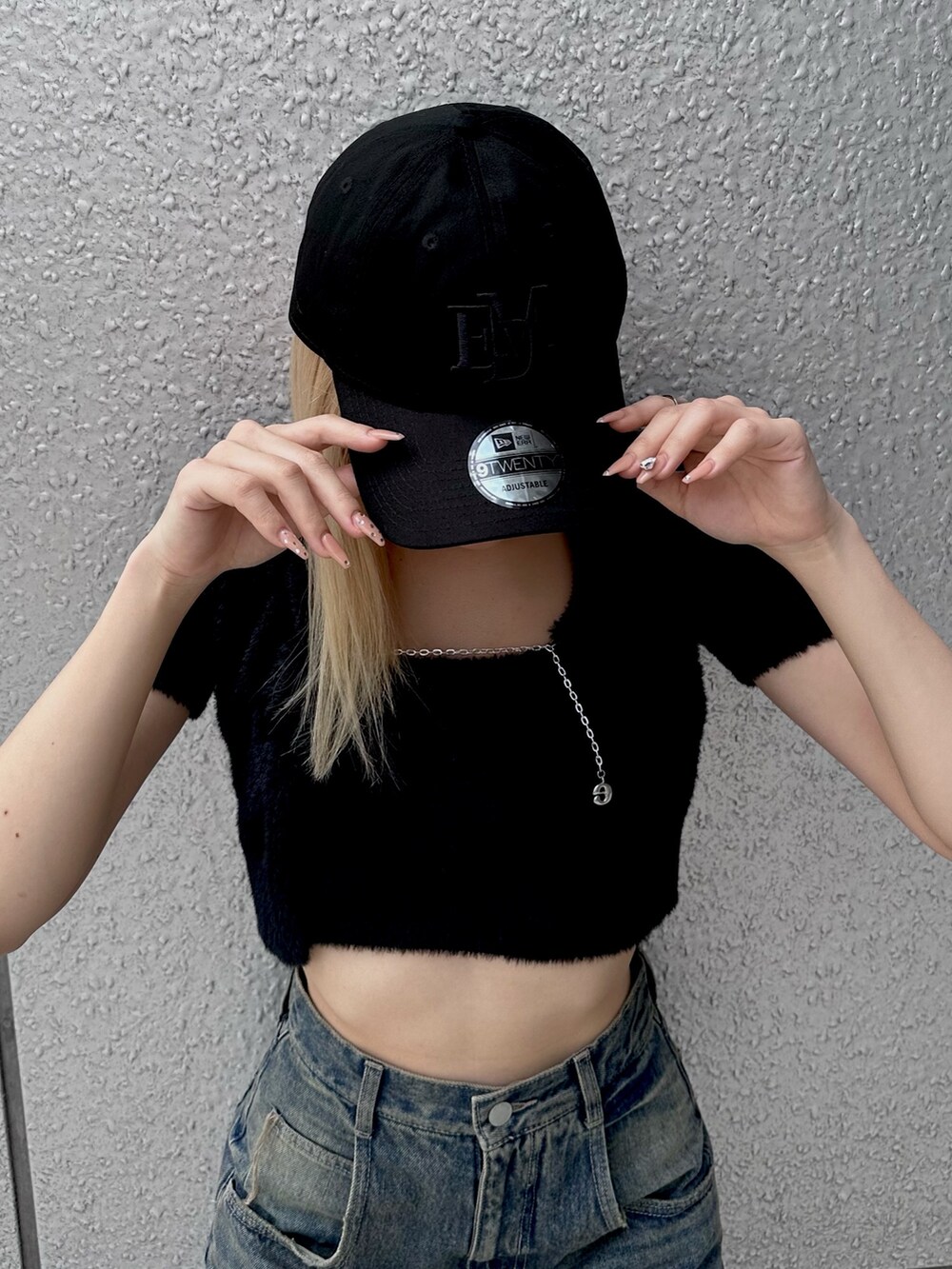 ブラック系のニット/セーター、ブルー系のデニムパンツ、ブラック系のキャップを着用したレディースの夏コーディネートの4枚目の写真