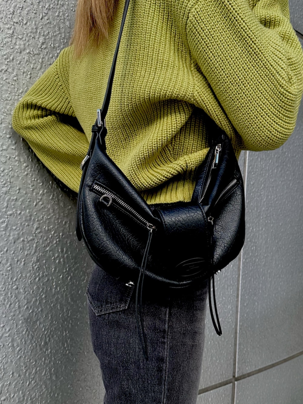 グリーン系のニット/セーター、ブラック系のデニムパンツ、ブラック系のハンドバッグを着用したレディースの冬コーディネートの3枚目の写真