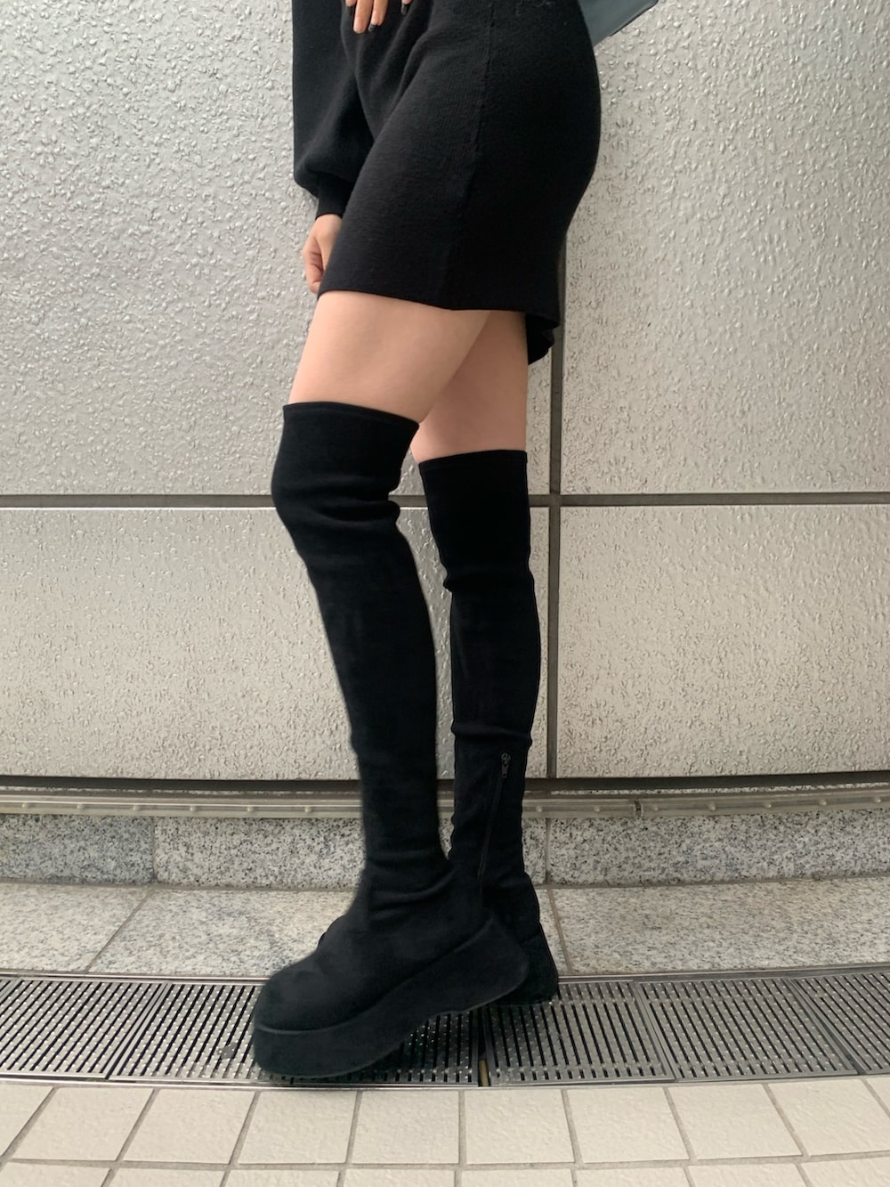 ブラック系のブーツ、ブラック系のワンピース、ブルー系のショルダーバッグを着用したレディースの冬コーディネートの3枚目の写真