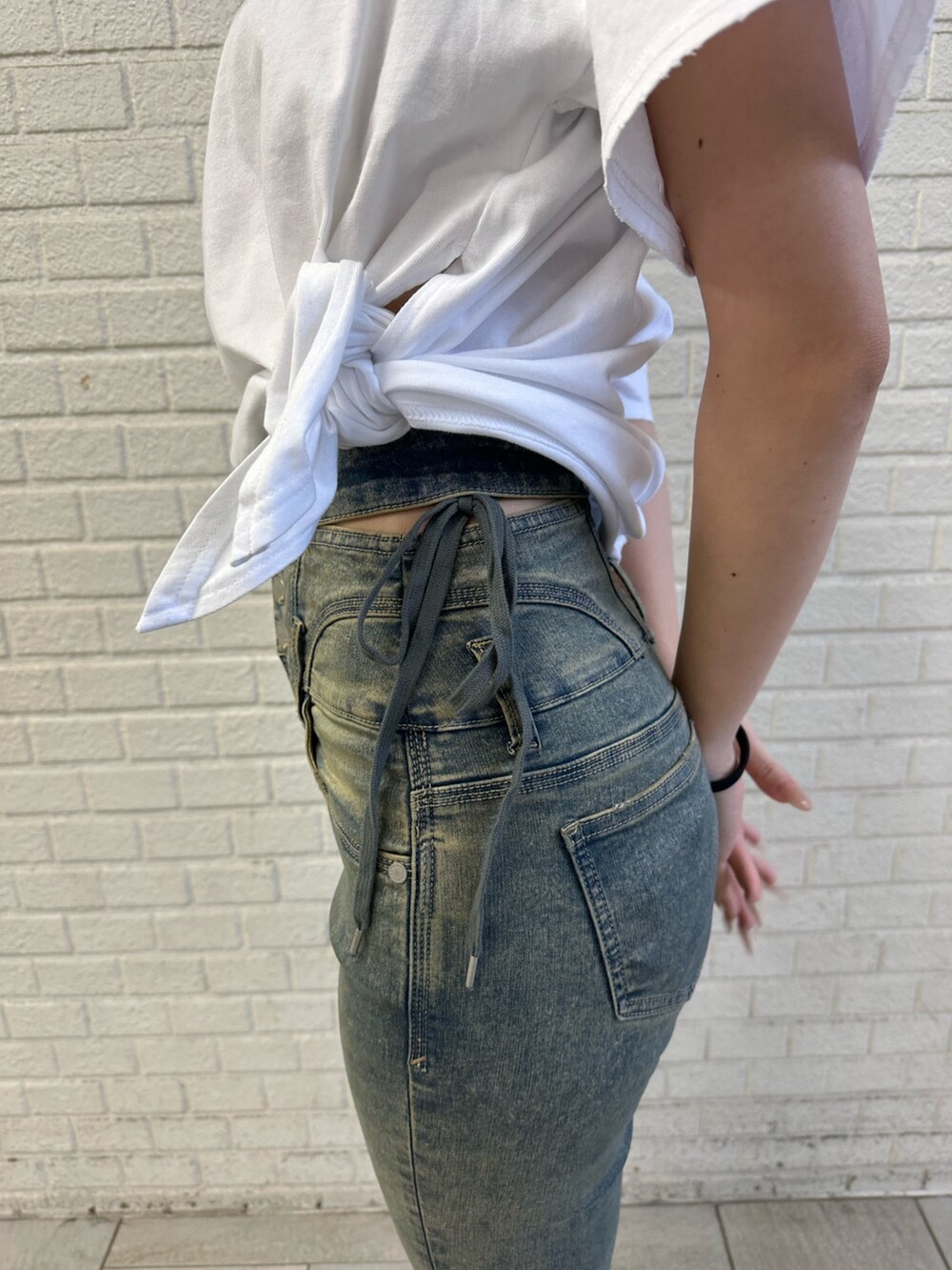 ホワイト系のTシャツ/カットソー、ブルー系のデニムパンツ、ブラック系のサンダルを着用したレディースの春コーディネートの4枚目の写真