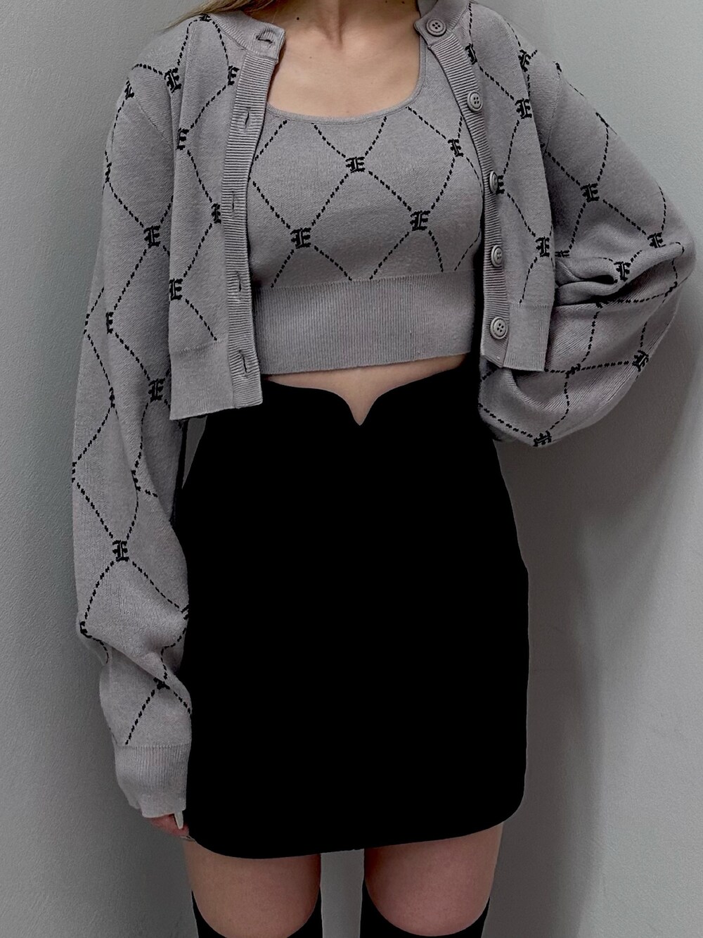 グレー系のニット/セーター、ブラック系のスカート、ブラック系のブーツを着用したレディースの秋コーディネートの3枚目の写真