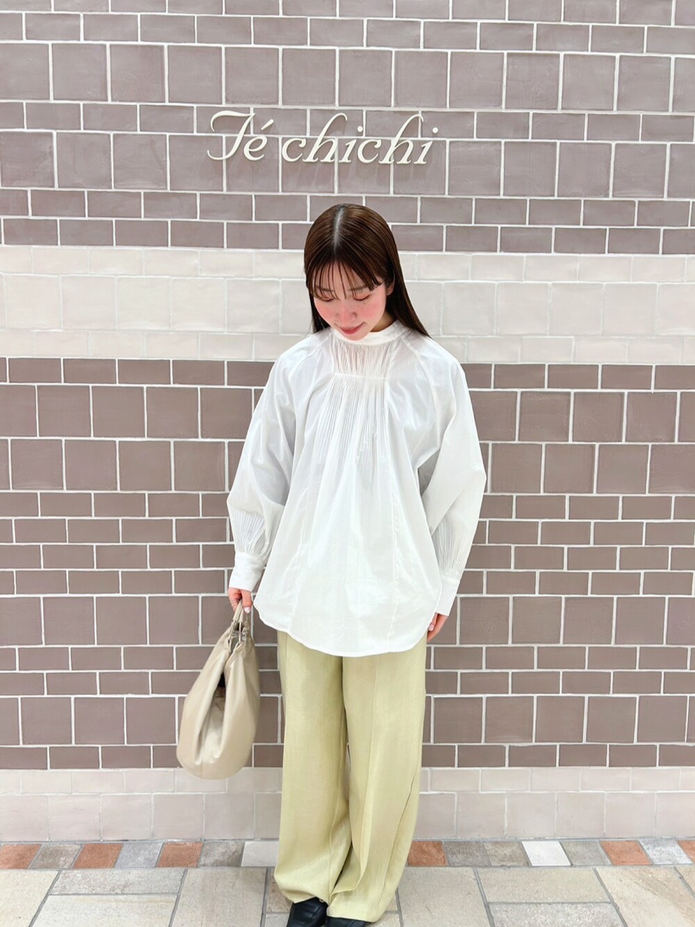 ホワイト系のシャツ/ブラウス、ベージュ系のトートバッグ、グリーン系のパンツを着用したレディースの春コーディネートの2枚目の写真