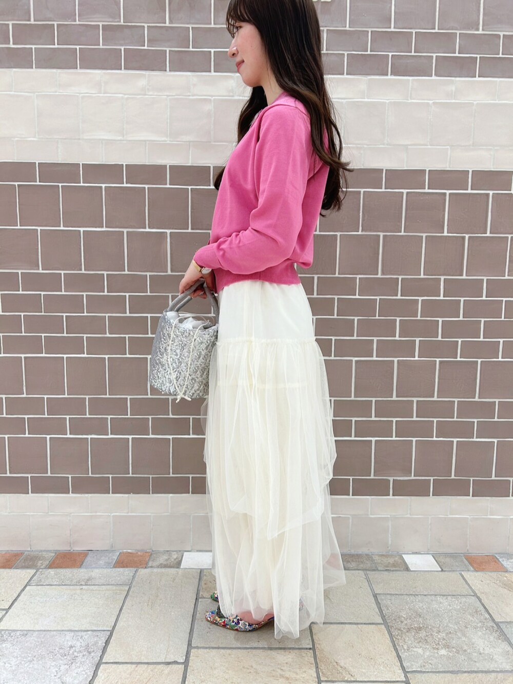 ピンク系のカーディガン/ボレロ、ホワイト系のスカート、ホワイト系のパンプスを着用したレディースの春コーディネートの2枚目の写真