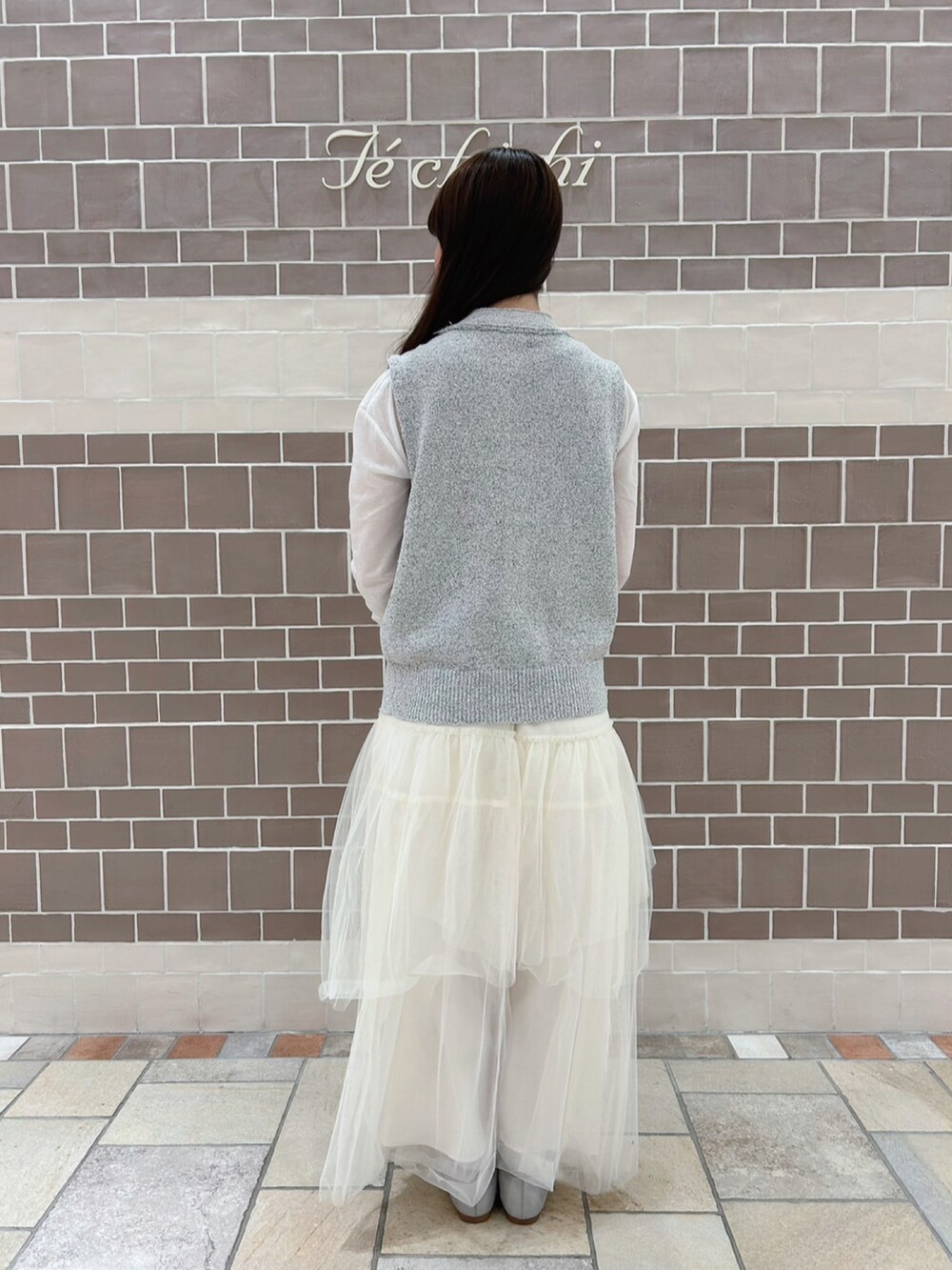 グレー系のニット/セーター、ホワイト系のTシャツ/カットソー、ホワイト系のスカートを着用したレディースの春コーディネートの3枚目の写真