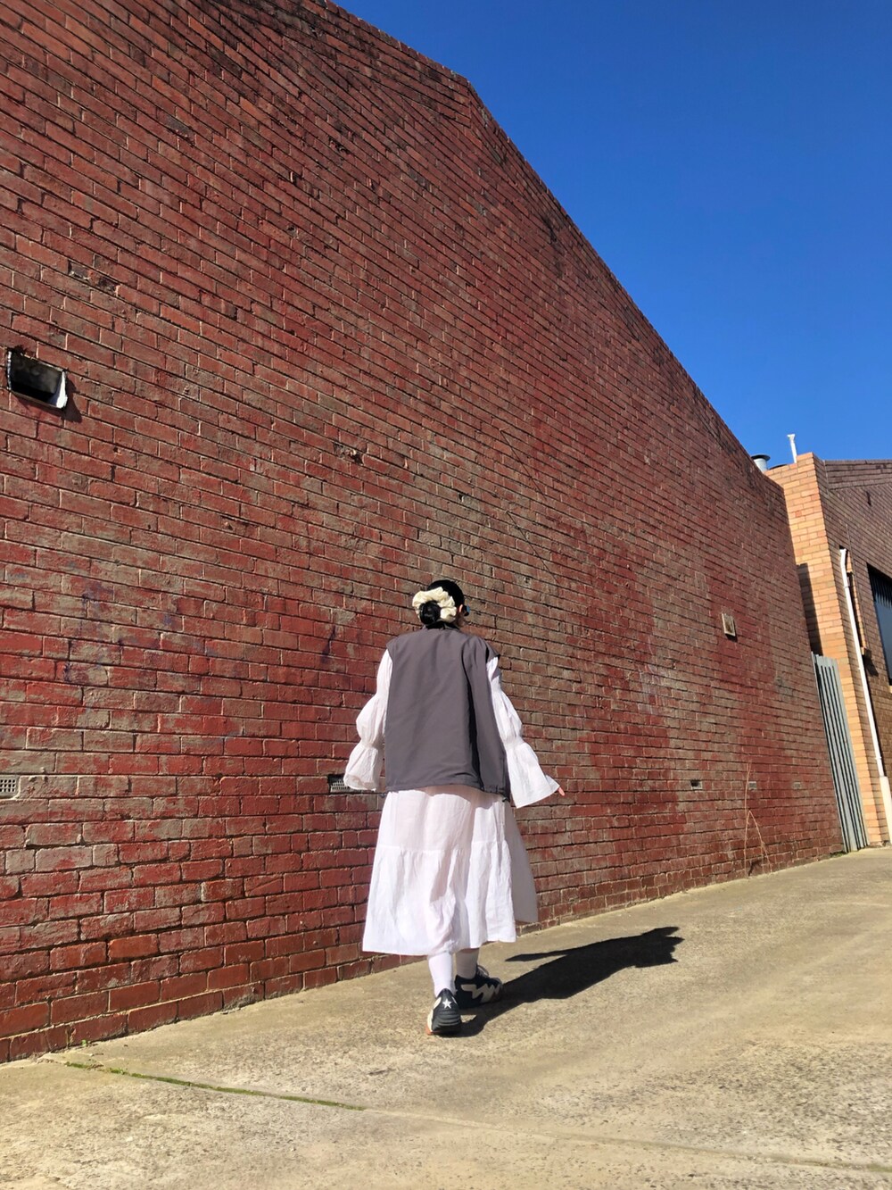 グレー系のミリタリージャケット、ブラック系のタンクトップ、ホワイト系のニット/セーターを着用したレディースの春コーディネートの3枚目の写真