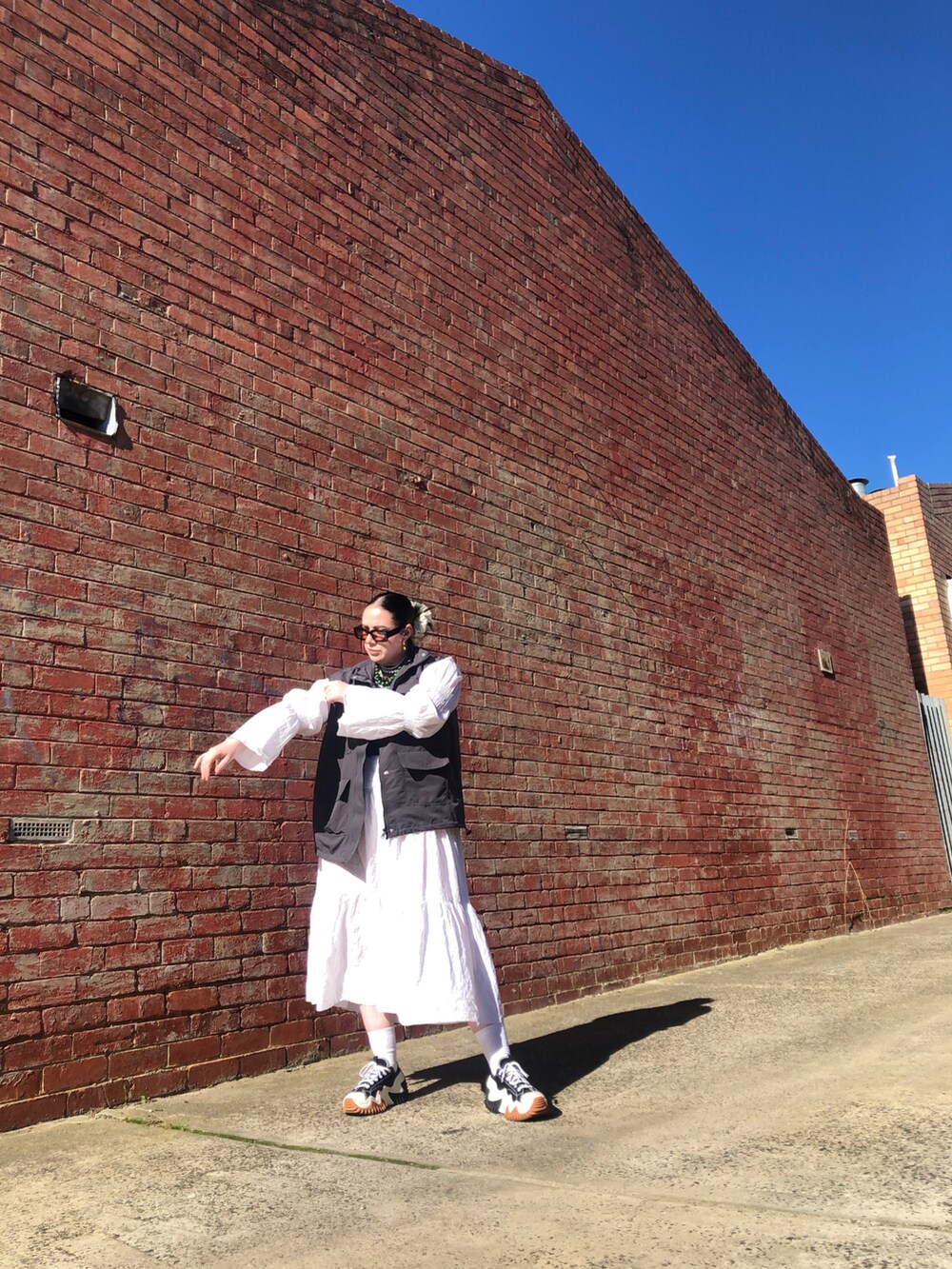 グレー系のミリタリージャケット、ブラック系のタンクトップ、ホワイト系のニット/セーターを着用したレディースの春コーディネートの2枚目の写真