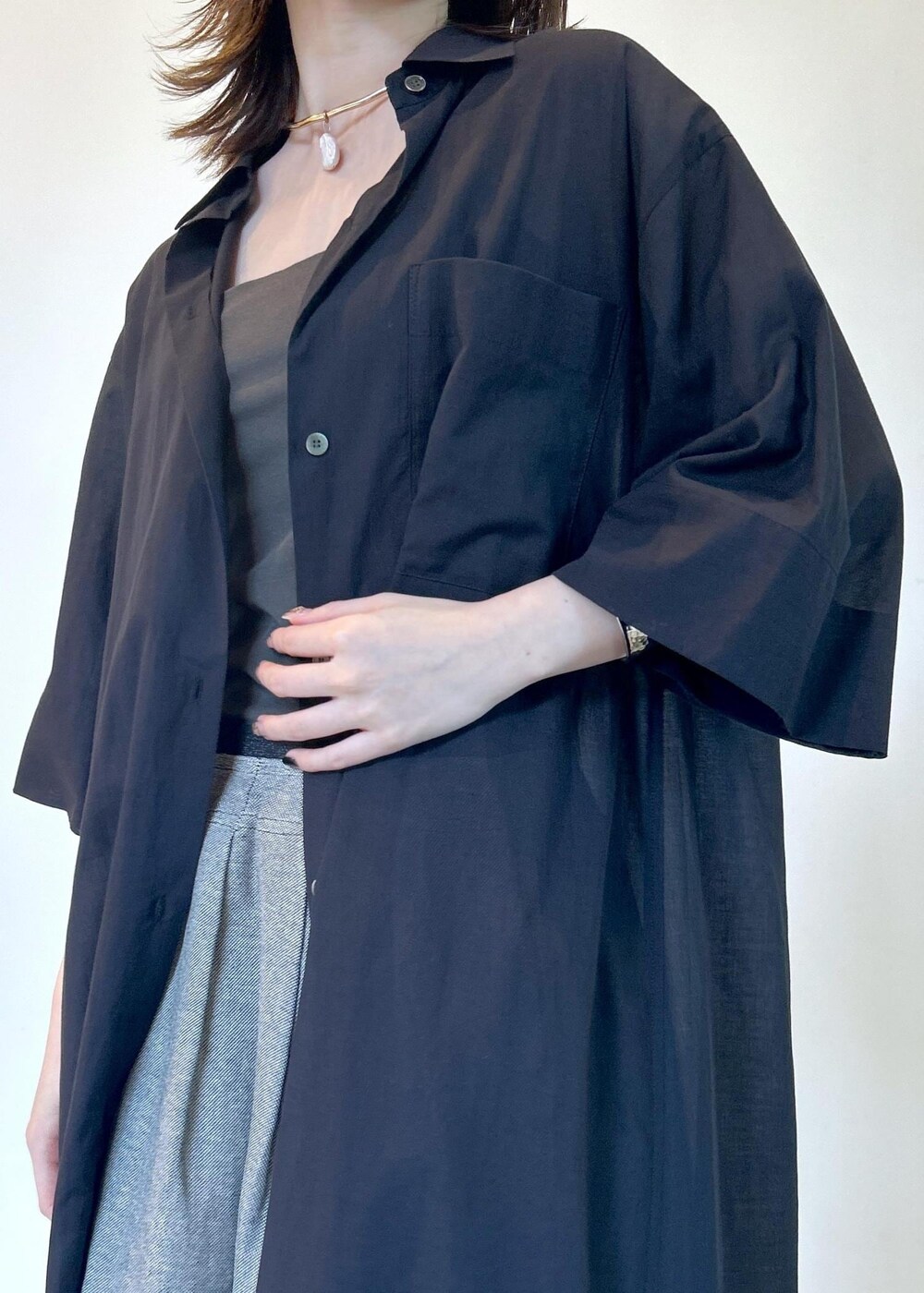 ブラック系のサンダル、ブラック系のシャツワンピース、グリーン系のタンクトップを着用したレディースの夏コーディネートの4枚目の写真