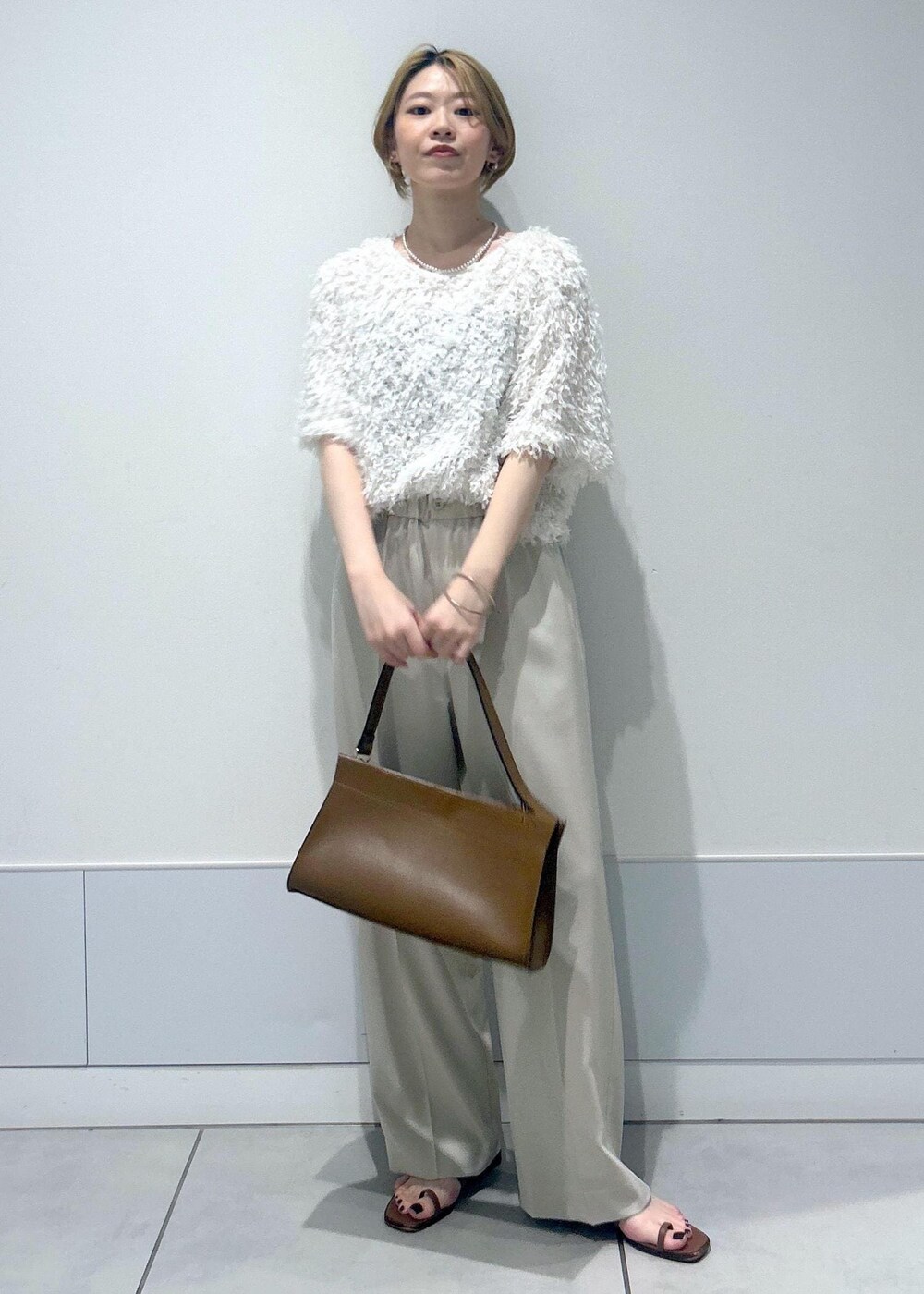 ブラウン系のショルダーバッグ、ホワイト系のTシャツ/カットソー、ベージュ系のその他パンツを着用したレディースの夏コーディネートの3枚目の写真