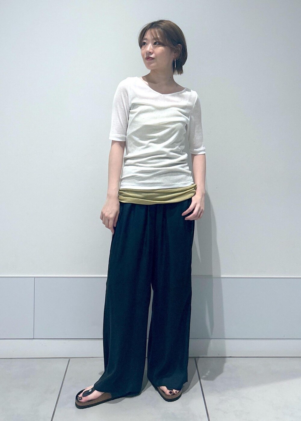 イエロー系のキャミソール、ホワイト系のTシャツ/カットソー、ブラック系のその他パンツを着用したレディースの春コーディネートの3枚目の写真