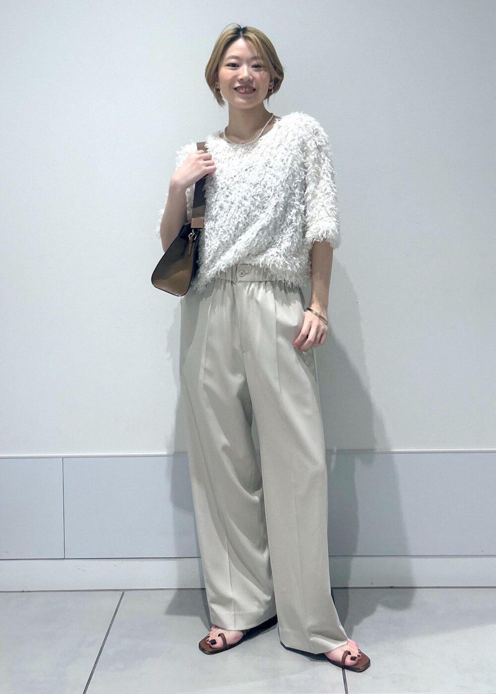 ブラウン系のショルダーバッグ、ホワイト系のTシャツ/カットソー、ベージュ系のその他パンツを着用したレディースの夏コーディネートの2枚目の写真