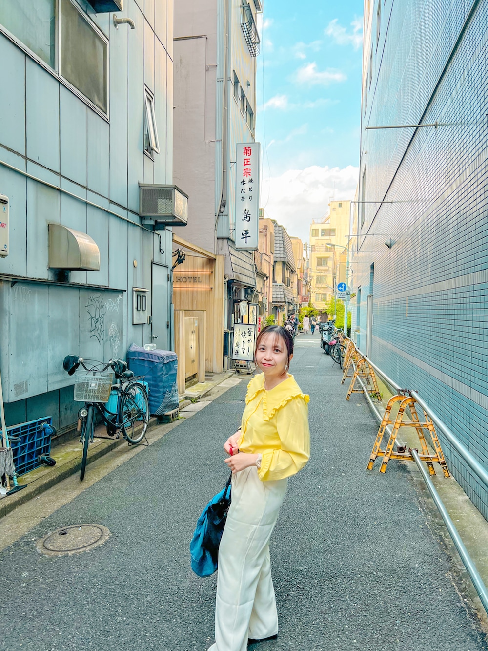 ホワイト系のスラックス、ブラック系のトートバッグ、イエロー系のシャツ/ブラウスを着用したレディースの夏コーディネートの2枚目の写真