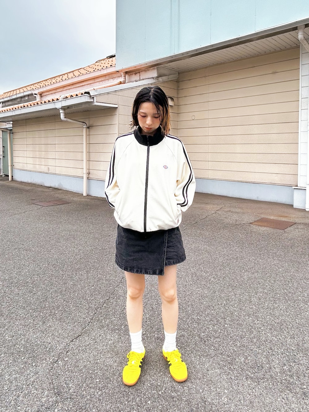 ホワイト系のジャージ、ブラック系のデニムスカート、イエロー系のスニーカーを着用したレディースの秋コーディネートの2枚目の写真