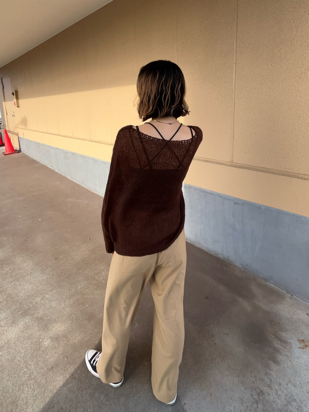 ブラウン系のニット/セーター、ブラック系のスラックス、ブラック系のスニーカーを着用したレディースの秋コーディネートの2枚目の写真