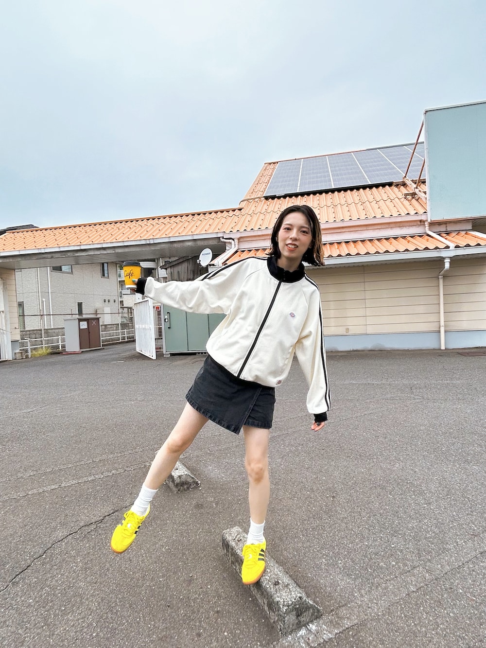 ホワイト系のジャージ、ブラック系のデニムスカート、イエロー系のスニーカーを着用したレディースの秋コーディネートの3枚目の写真