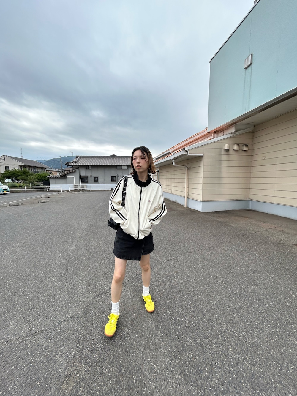 ホワイト系のジャージ、ブラック系のデニムスカート、イエロー系のスニーカーを着用したレディースの秋コーディネートの4枚目の写真