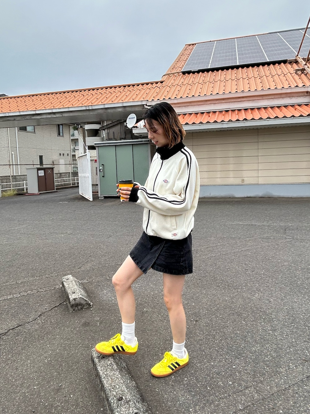 ホワイト系のジャージ、ブラック系のデニムスカート、イエロー系のスニーカーを着用したレディースの秋コーディネートの5枚目の写真