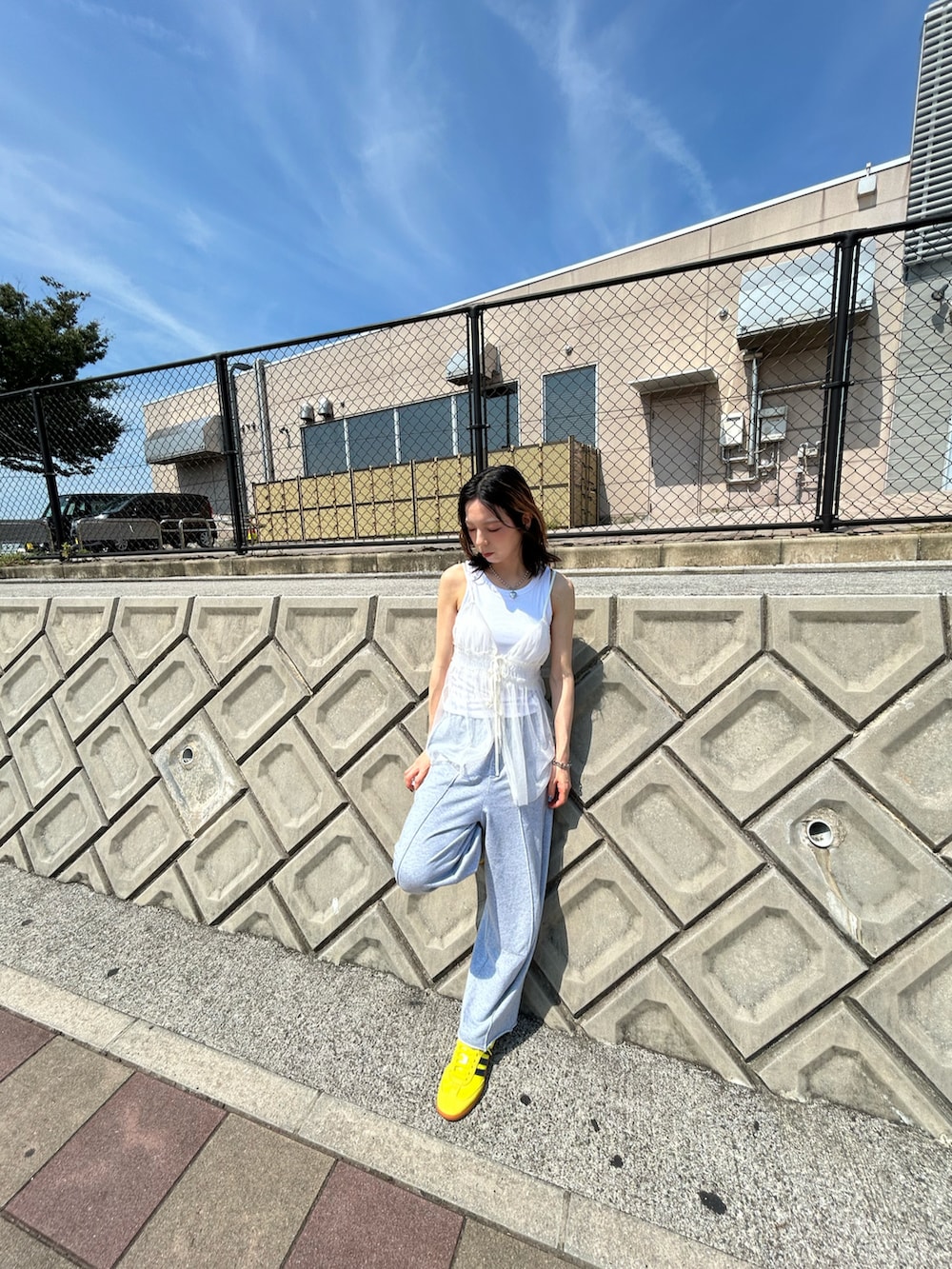 ホワイト系のキャミソール、グレー系のスウェットパンツ、イエロー系のスニーカーを着用したレディースの夏コーディネートの2枚目の写真
