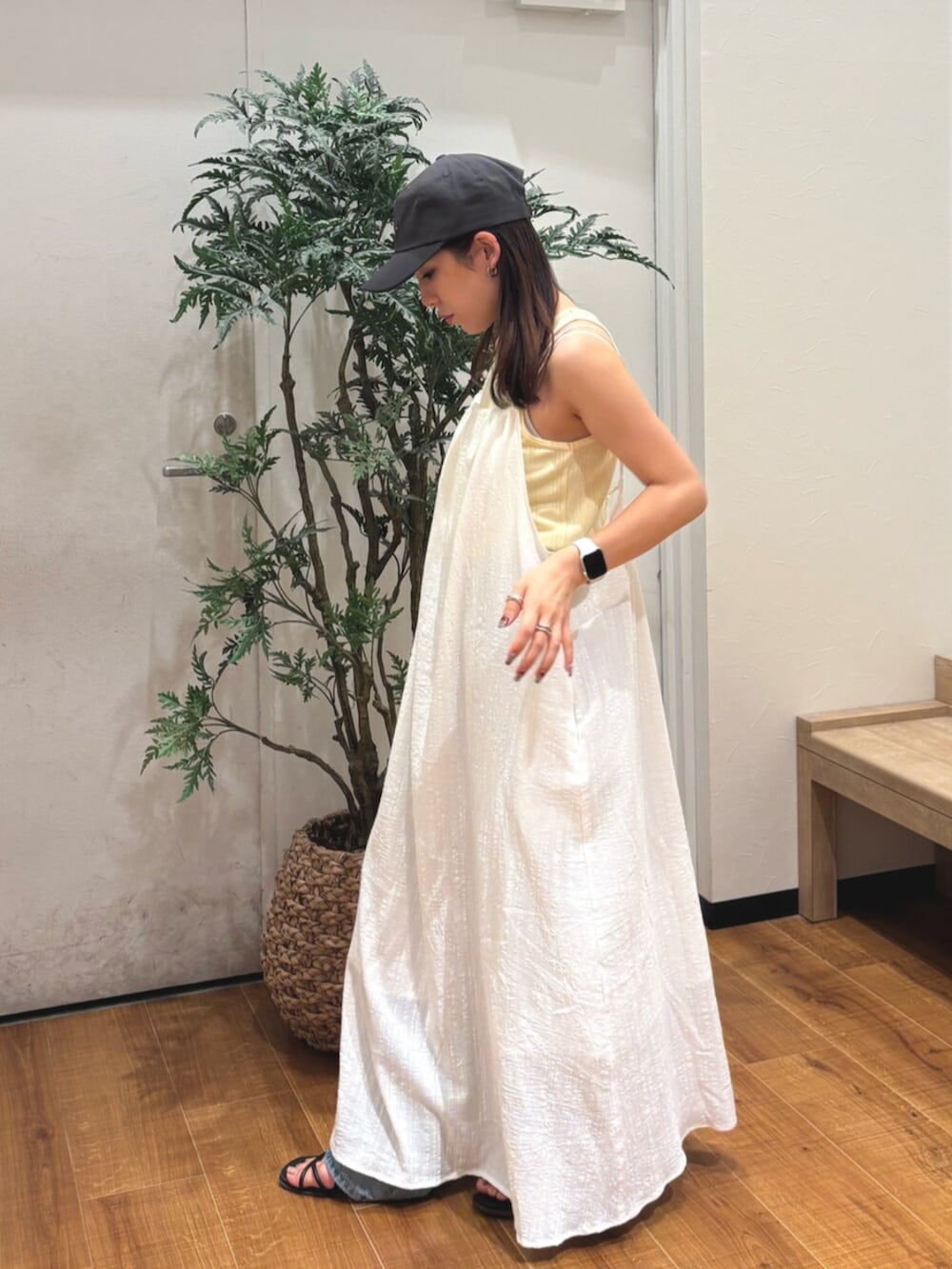 イエロー系のタンクトップ、ホワイト系のワンピース、ブルー系のデニムパンツを着用したレディースの夏コーディネートの2枚目の写真