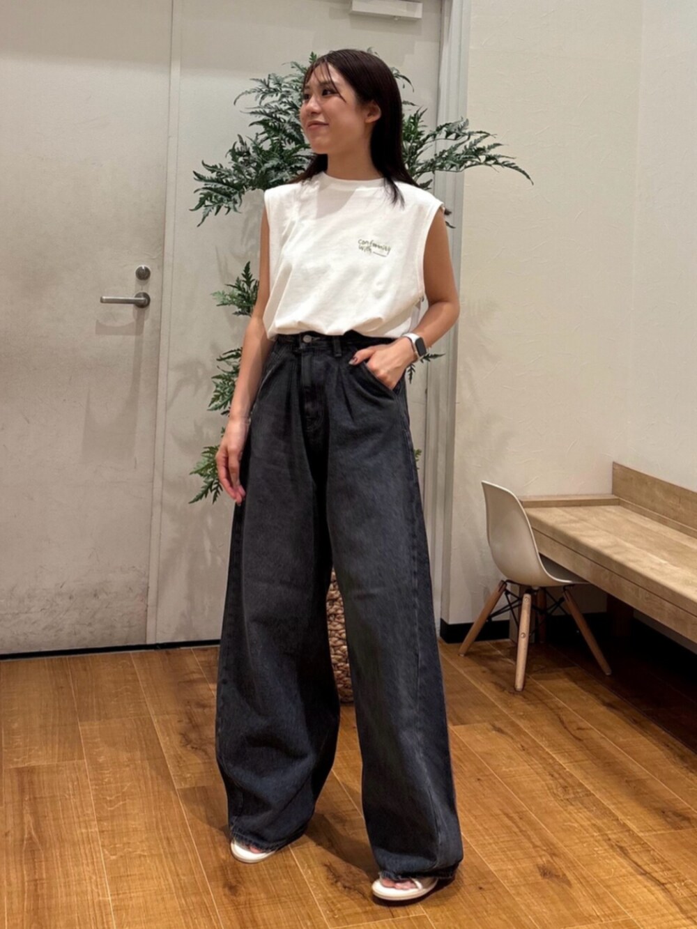 ホワイト系のタンクトップ、ブラック系のデニムパンツ、ホワイト系のサンダルを着用したレディースの夏コーディネートの2枚目の写真