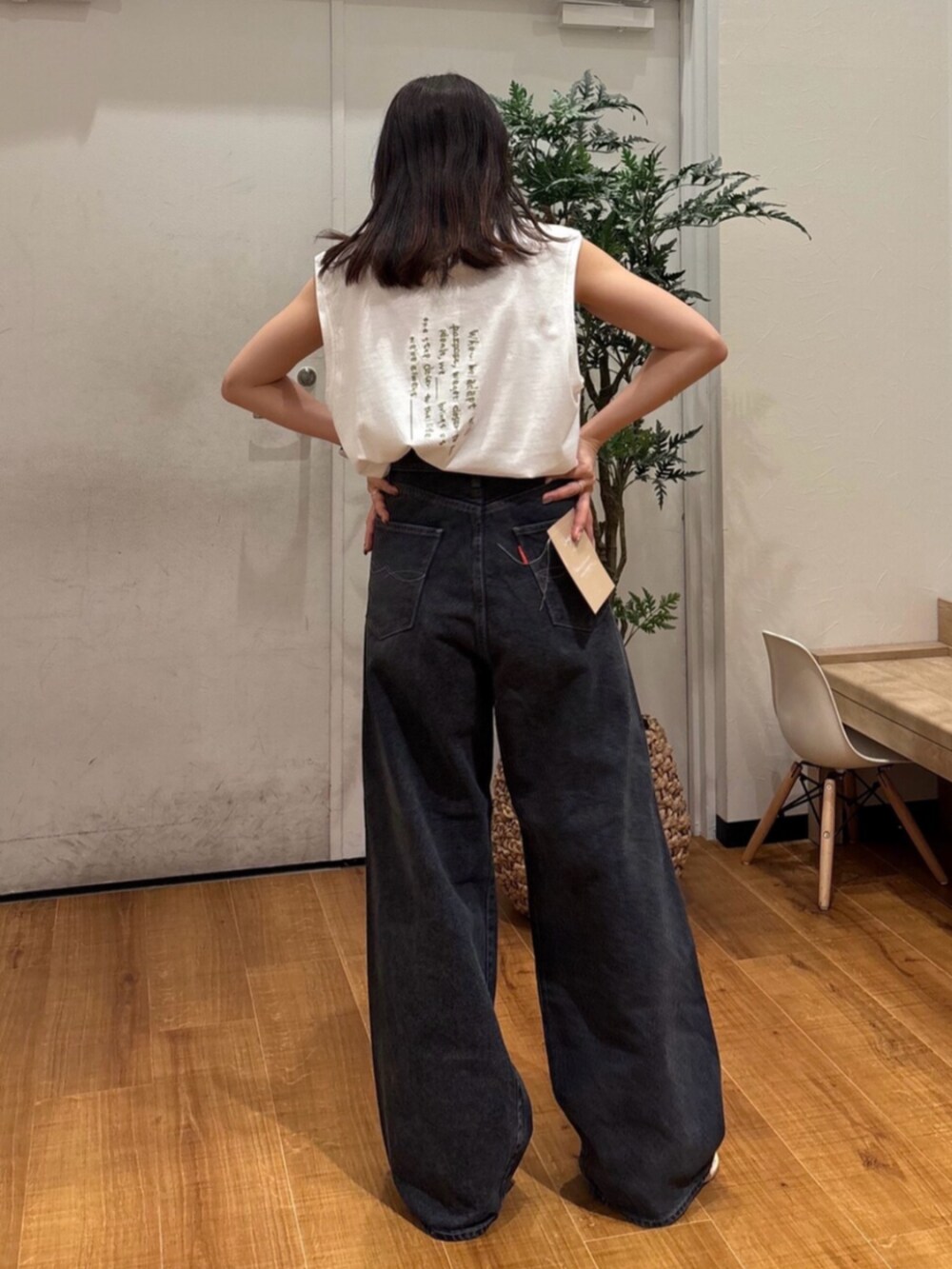 ホワイト系のタンクトップ、ブラック系のデニムパンツ、ホワイト系のサンダルを着用したレディースの夏コーディネートの4枚目の写真