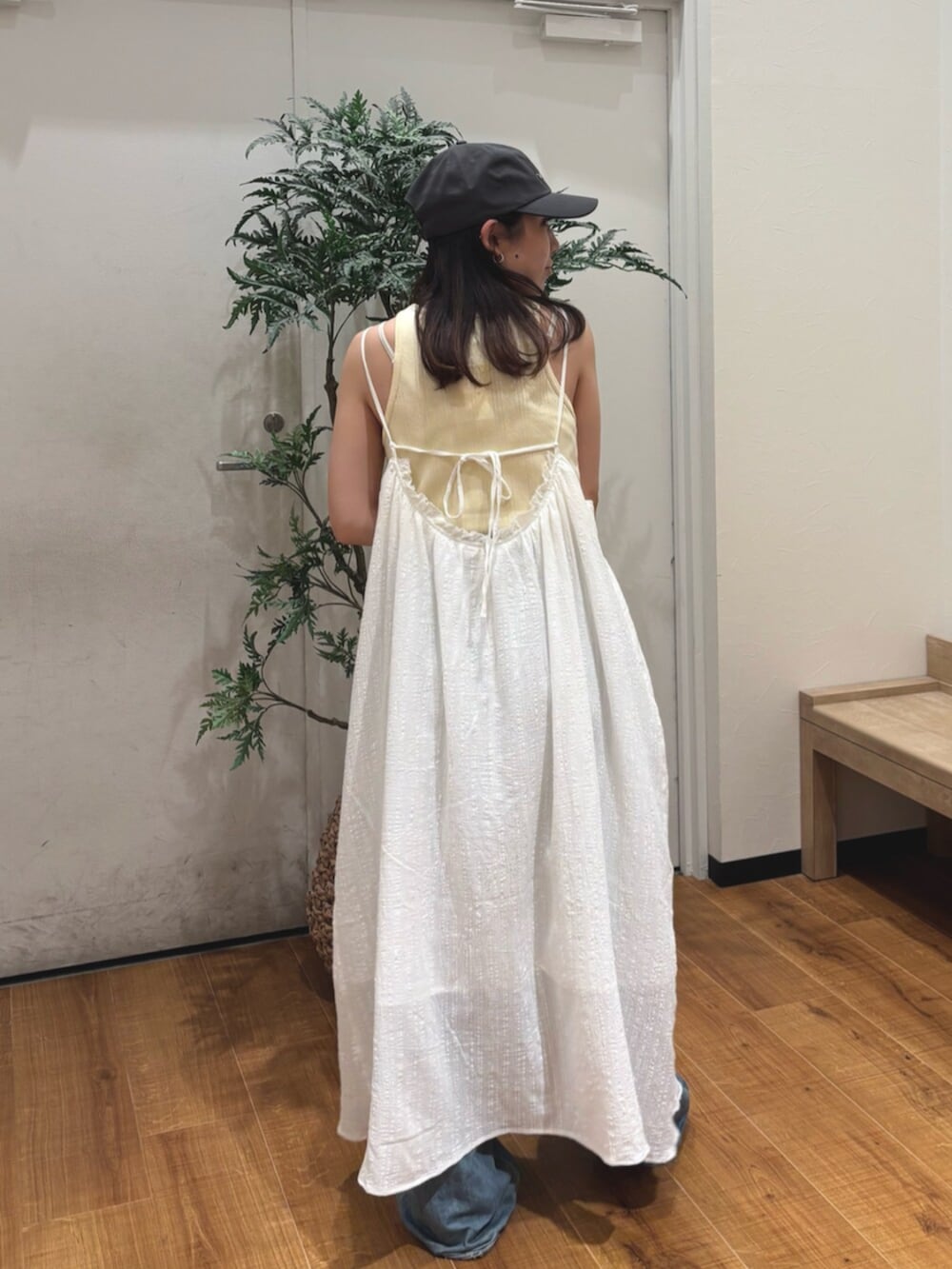 イエロー系のタンクトップ、ホワイト系のワンピース、ブルー系のデニムパンツを着用したレディースの夏コーディネートの4枚目の写真