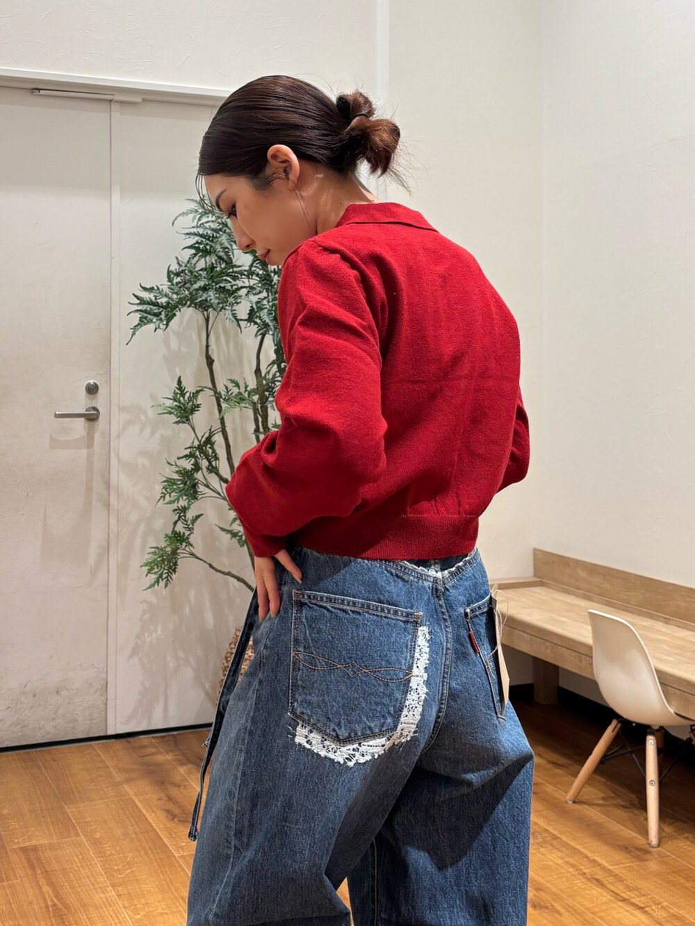 レッド系のカーディガン/ボレロ、ブルー系のデニムパンツ、ゴールド系のバレエシューズを着用したレディースの秋コーディネートの5枚目の写真