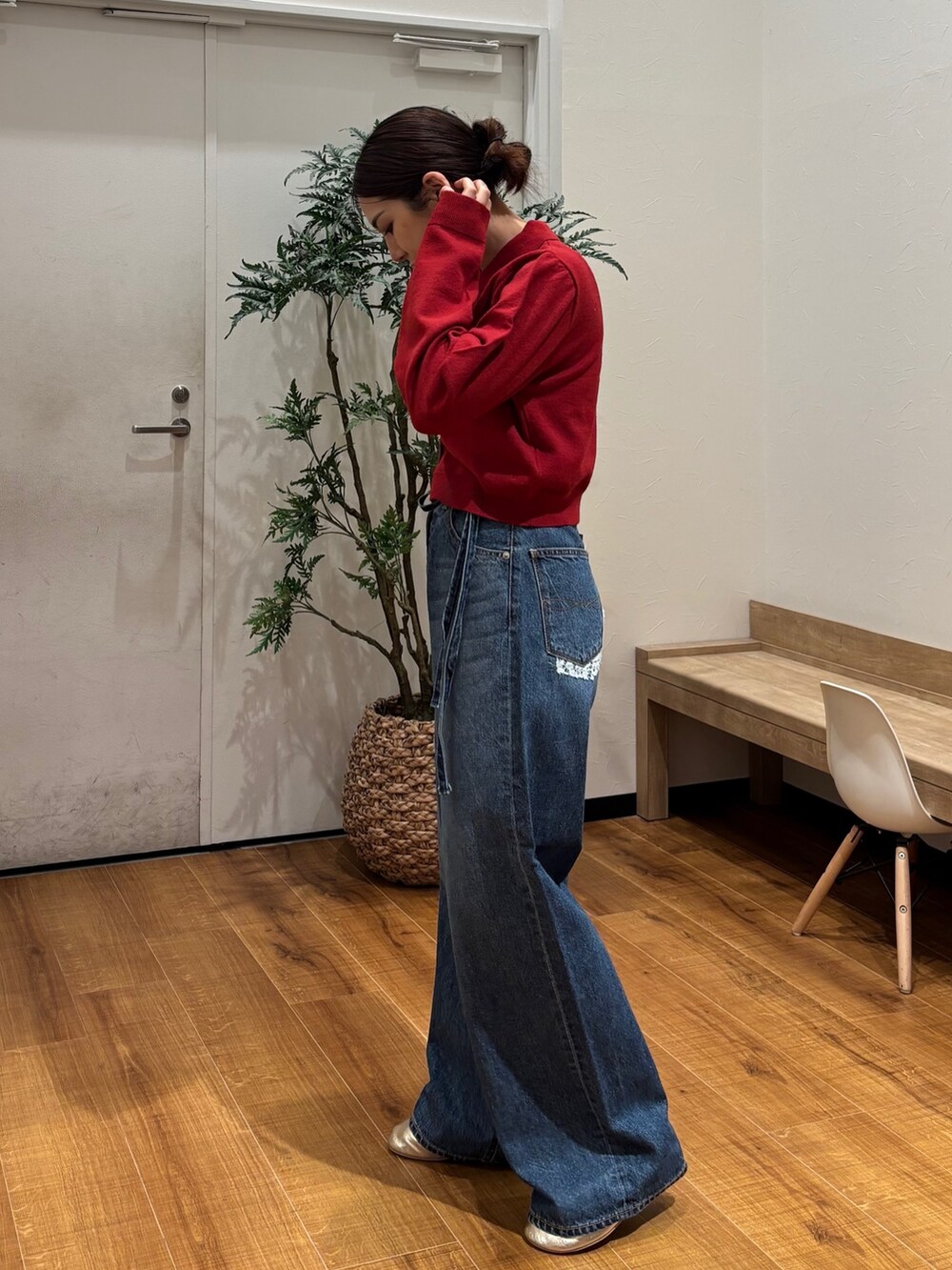 レッド系のカーディガン/ボレロ、ブルー系のデニムパンツ、ゴールド系のバレエシューズを着用したレディースの秋コーディネートの3枚目の写真