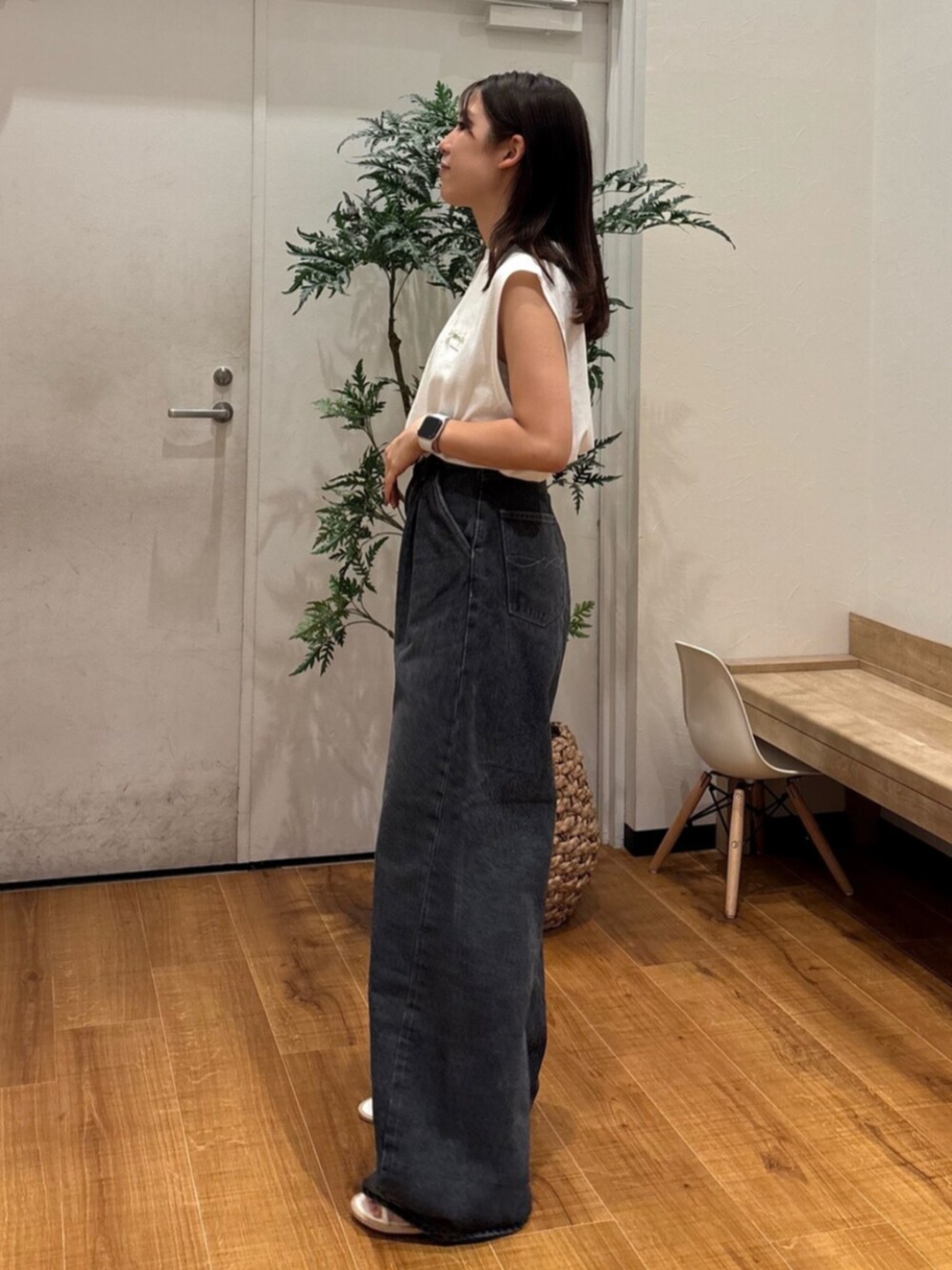ホワイト系のタンクトップ、ブラック系のデニムパンツ、ホワイト系のサンダルを着用したレディースの夏コーディネートの3枚目の写真