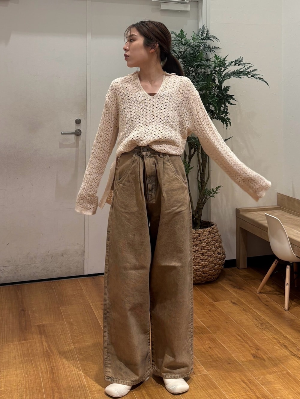 ベージュ系のニット/セーター、ブラウン系のデニムパンツを着用したレディースの春コーディネートの2枚目の写真