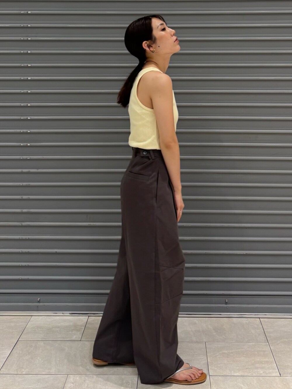 シルバー系のサンダル、イエロー系のタンクトップ、グレー系のチノパンツを着用したレディースの夏コーディネートの4枚目の写真