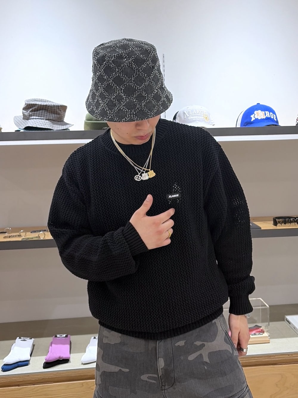 ブラック系のニット/セーター、ブラック系のカーゴパンツ、ブラック系のハットを着用したメンズの春コーディネートの6枚目の写真