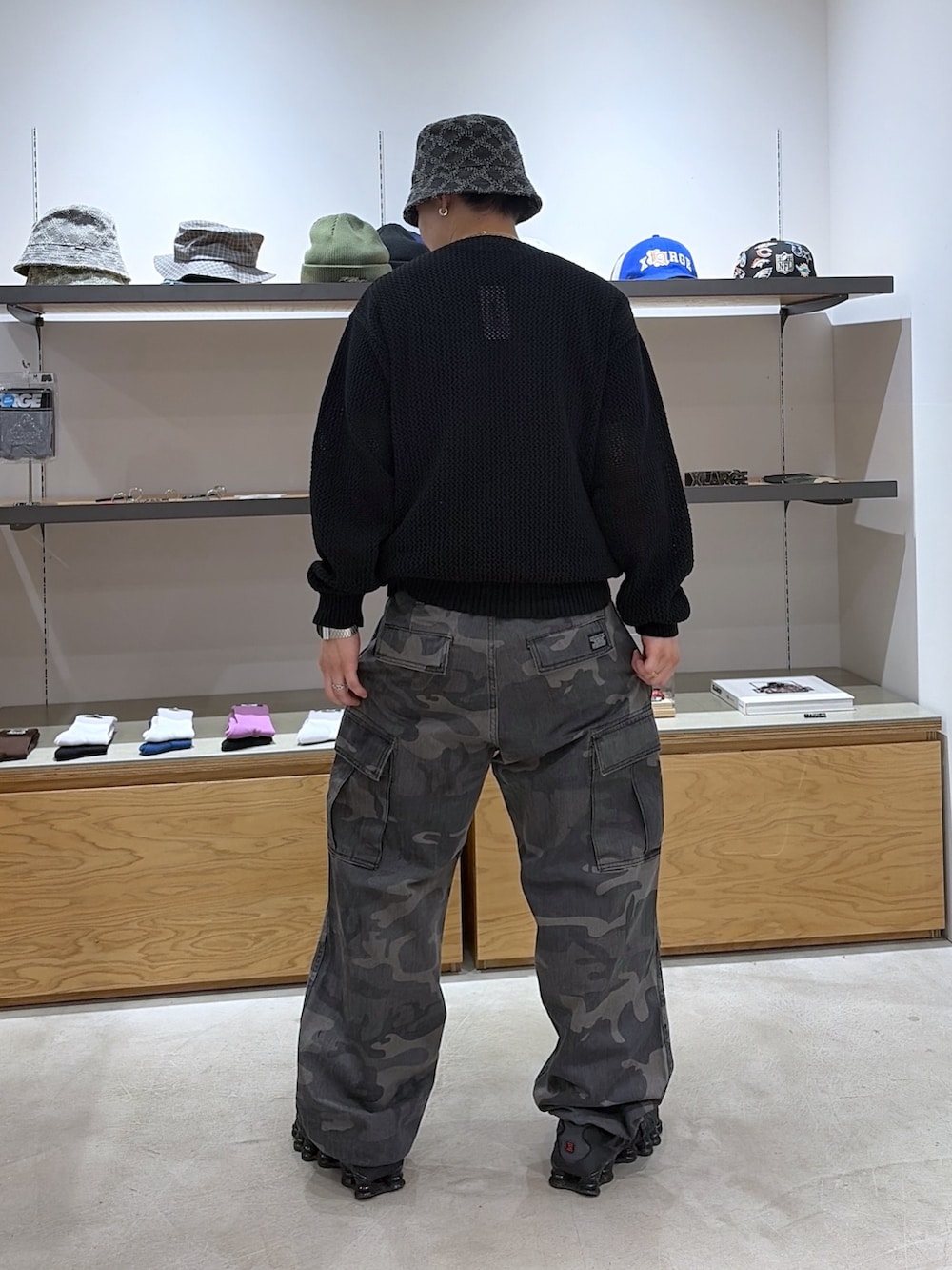 ブラック系のニット/セーター、ブラック系のカーゴパンツ、ブラック系のハットを着用したメンズの春コーディネートの3枚目の写真