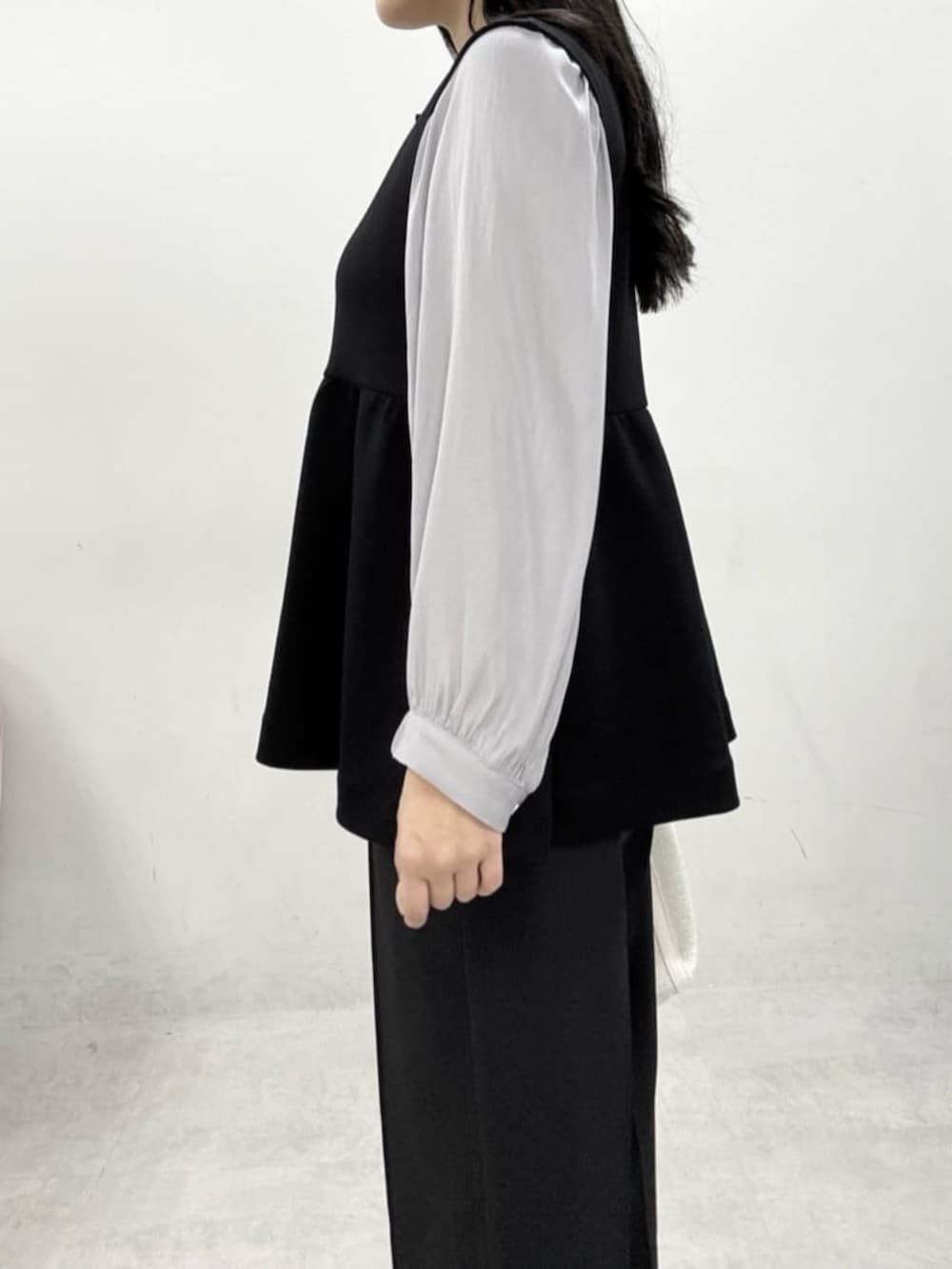 ホワイト系のハンドバッグ、グレー系のサンダル、ブラック系のスラックスを着用したレディースの冬コーディネートの6枚目の写真