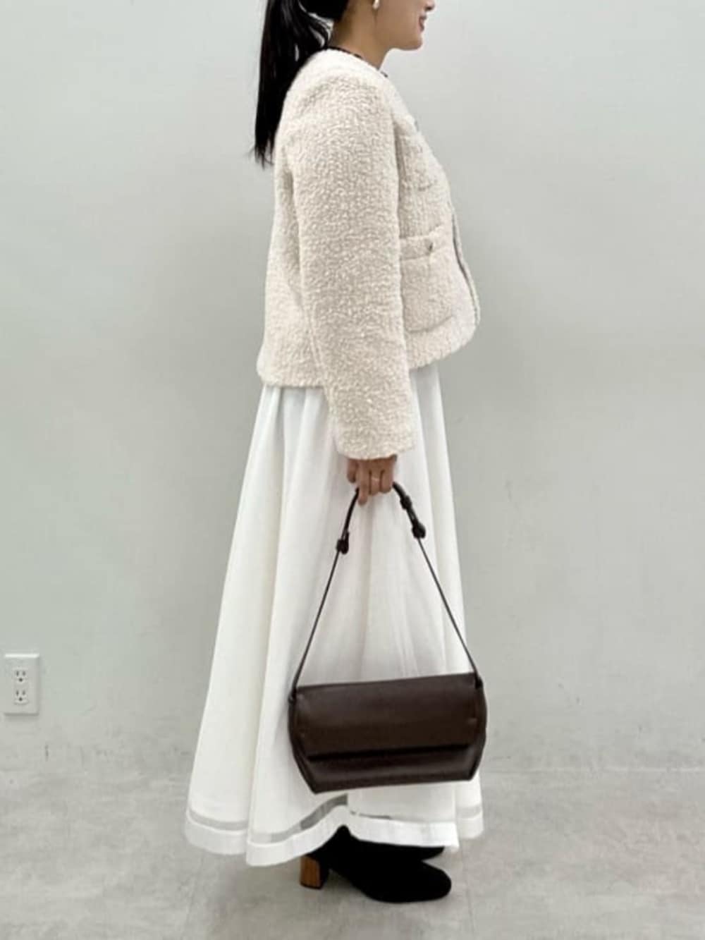 ブラック系のニット/セーター、ホワイト系のスカート、ホワイト系のノーカラージャケットを着用したレディースの秋コーディネートの2枚目の写真