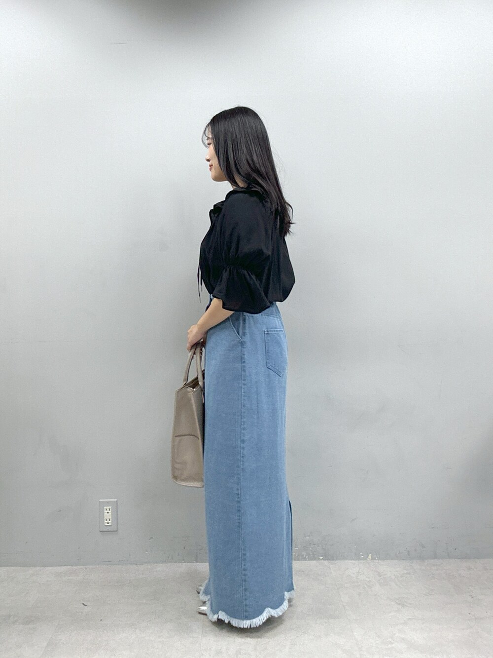 ベージュ系のショルダーバッグ、ブラック系のシャツ/ブラウス、ブルー系のスカートを着用したレディースの春コーディネートの2枚目の写真