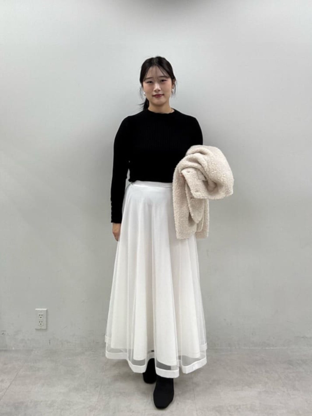 ブラック系のニット/セーター、ホワイト系のスカート、ホワイト系のノーカラージャケットを着用したレディースの秋コーディネートの4枚目の写真