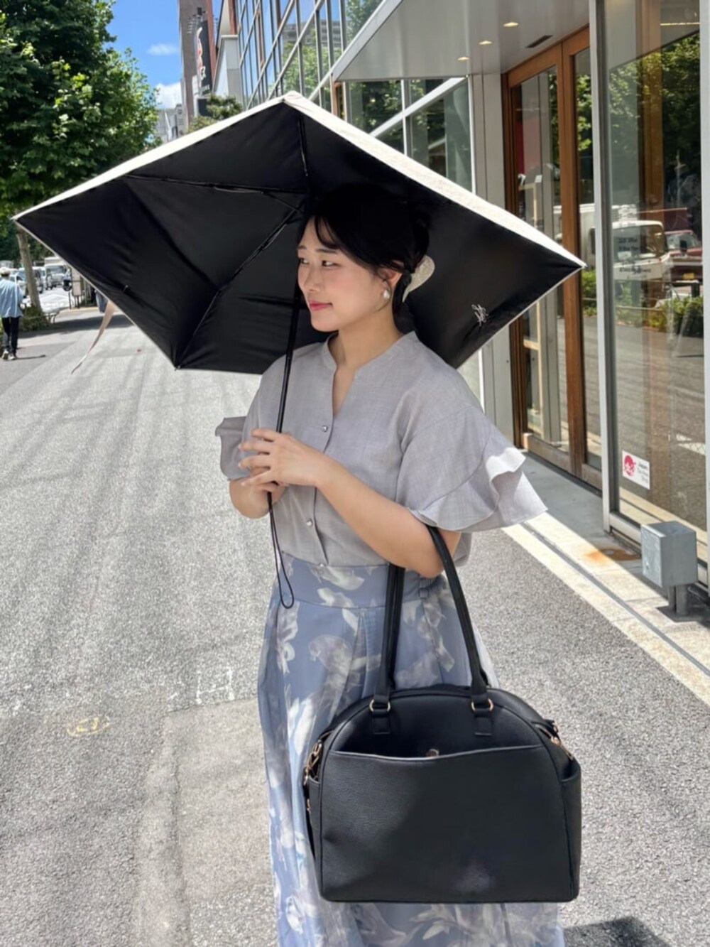 グレー系のシャツ/ブラウス、ブラック系のボストンバッグ、ブルー系のスカートを着用したレディースの夏コーディネートの6枚目の写真