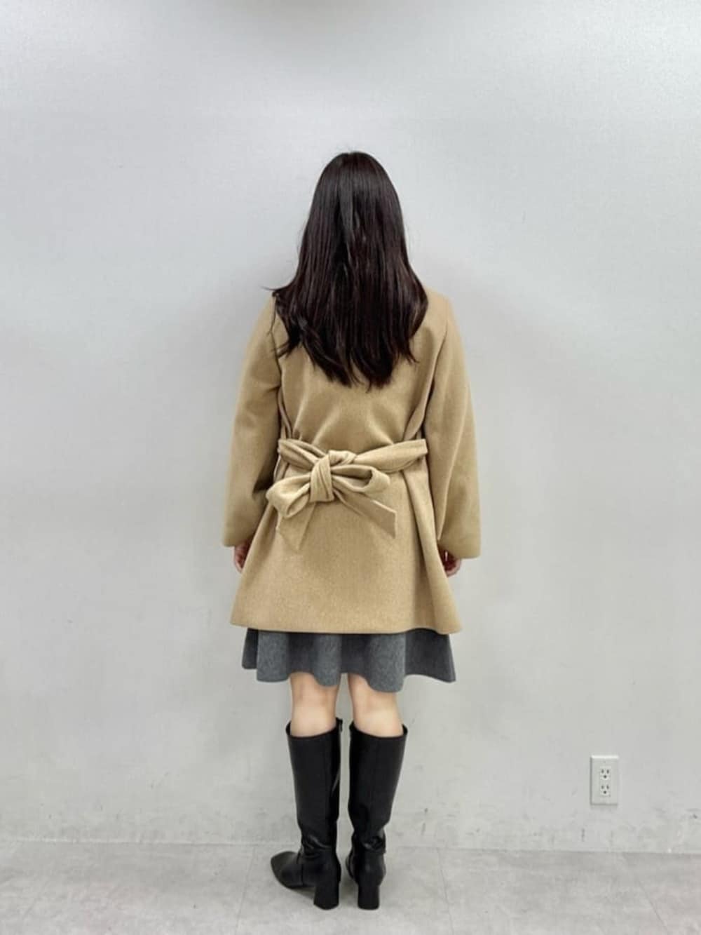 ブラック系のブーツ、ベージュ系のその他アウター、グレー系のワンピースを着用したレディースの秋コーディネートの3枚目の写真