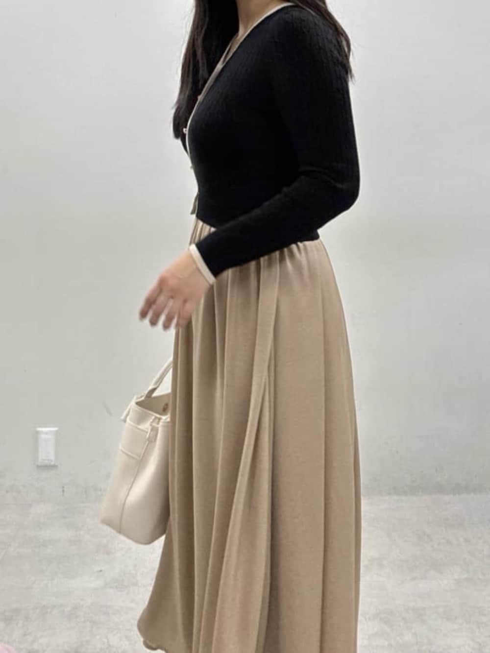 ホワイト系のショルダーバッグ、ホワイト系のサンダル、ブラック系のワンピースを着用したレディースの冬コーディネートの4枚目の写真