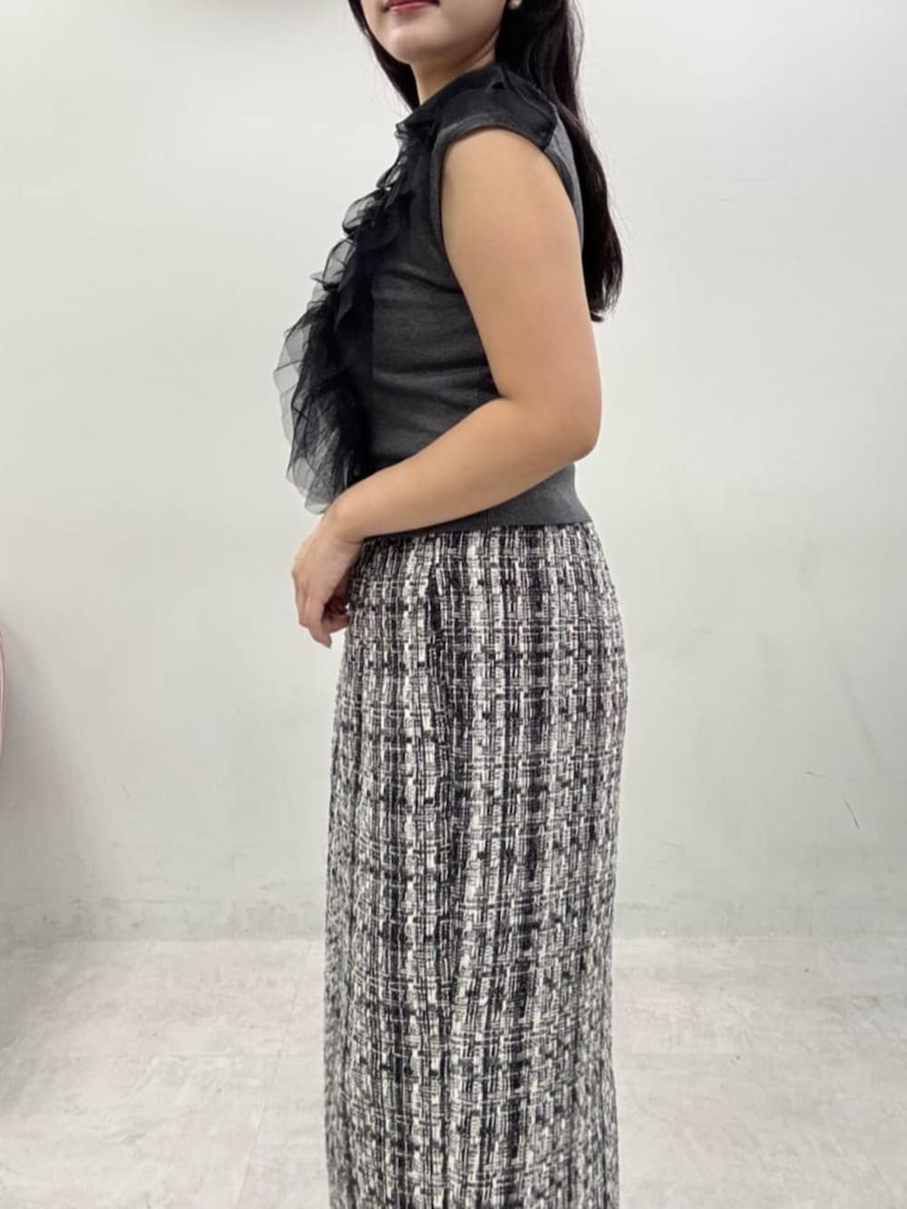 グレー系のスカート、ブラック系のブーツ、グレー系のベストを着用したレディースの秋コーディネートの4枚目の写真