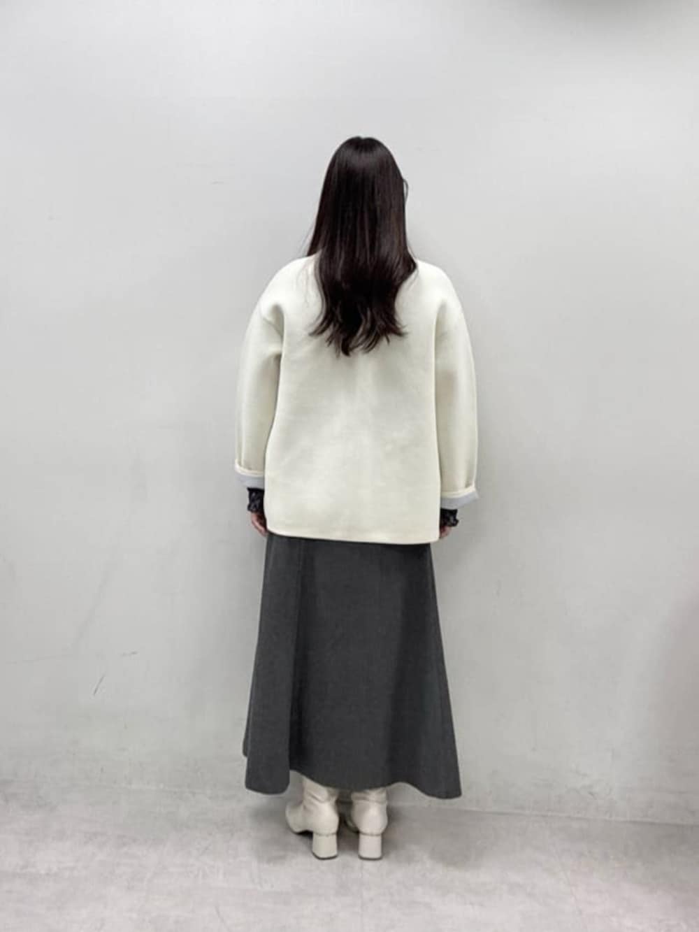 ホワイト系のカーディガン/ボレロ、ブルー系のTシャツ/カットソー、グレー系のスカートを着用したレディースの冬コーディネートの3枚目の写真