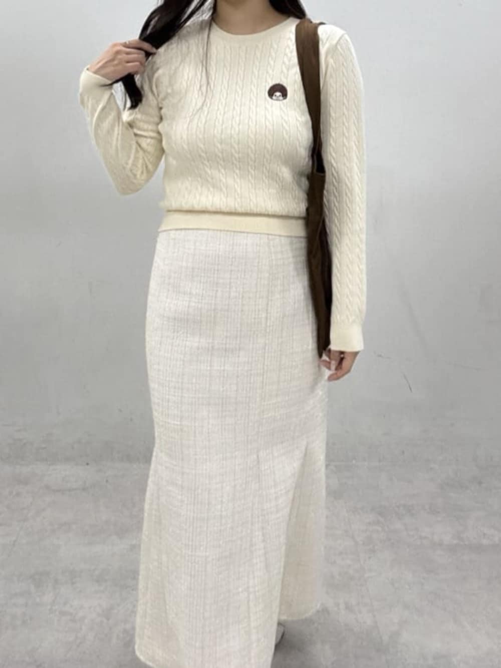 ホワイト系のスカート、ブラウン系のトートバッグ、ホワイト系のニット/セーターを着用したレディースの冬コーディネートの2枚目の写真