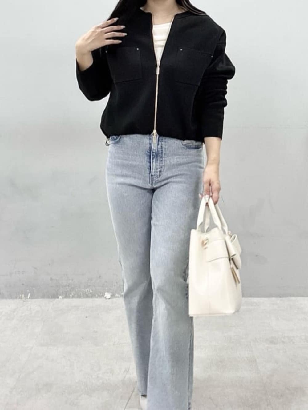 ブルー系のデニムパンツ、ホワイト系のニット/セーター、ブラック系のブルゾンを着用したレディースの春コーディネートの3枚目の写真