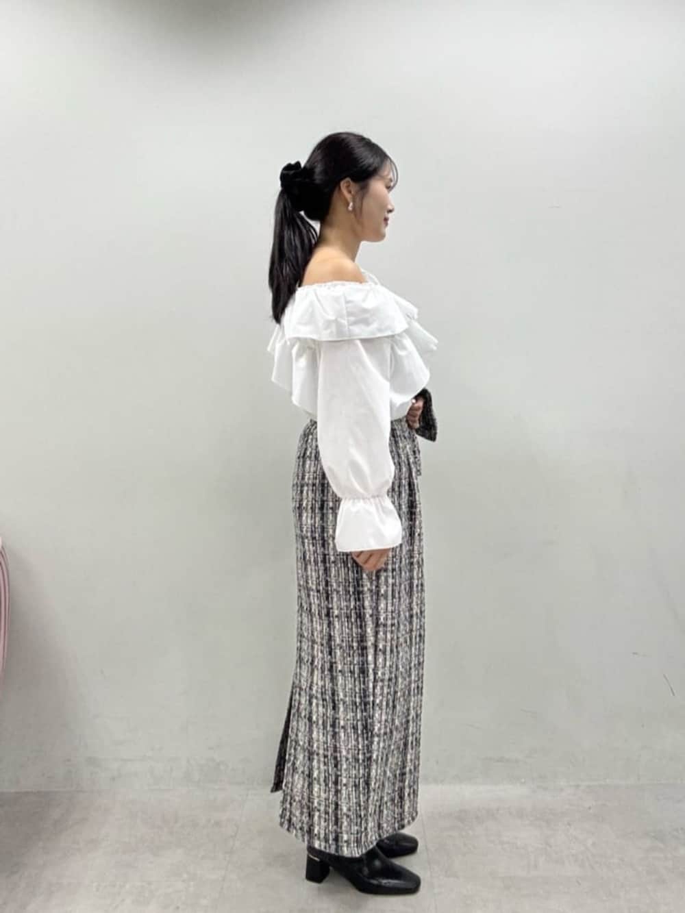 グレー系のスカート、グレー系のノーカラージャケット、ブラック系のブーツを着用したレディースの秋コーディネートの2枚目の写真