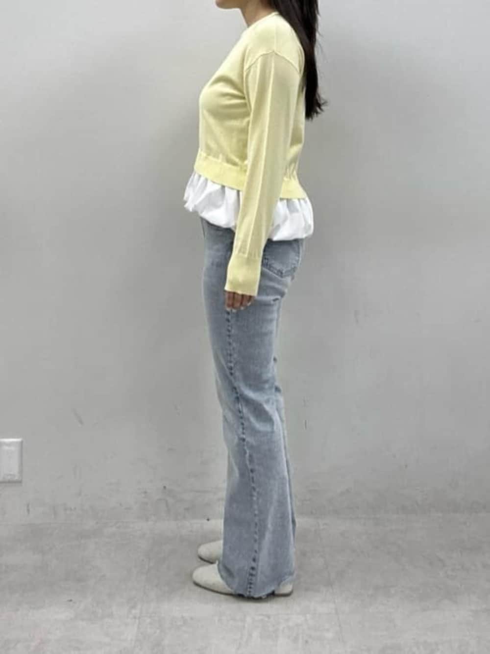 ブルー系のデニムパンツ、ホワイト系のサンダル、イエロー系のニット/セーターを着用したレディースの冬コーディネートの2枚目の写真