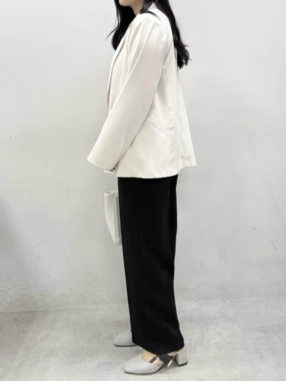 ホワイト系のテーラードジャケット、ホワイト系のハンドバッグ、グレー系のサンダルを着用したレディースの冬コーディネートの3枚目の写真