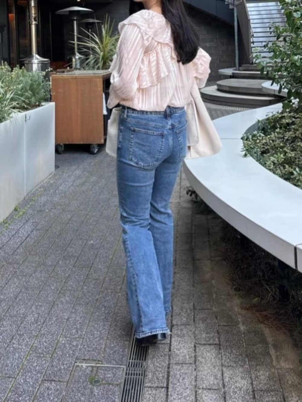 ブルー系のデニムパンツ、ホワイト系のハンドバッグ、ピンク系のシャツ/ブラウスを着用したレディースの冬コーディネートの3枚目の写真