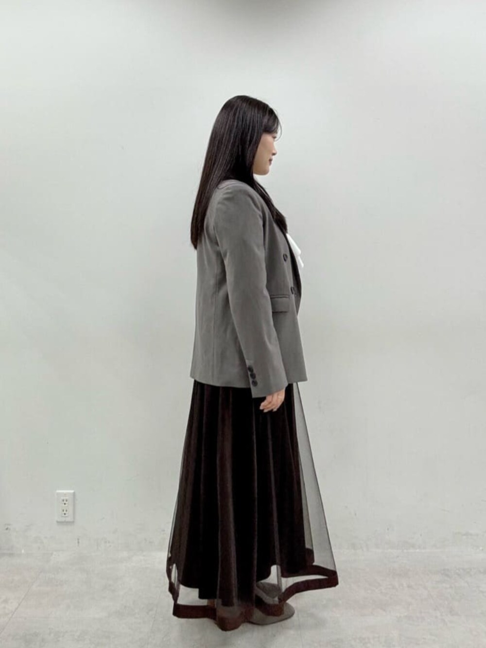 ブラウン系のスカート、グレー系のテーラードジャケットを着用したレディースの秋コーディネートの2枚目の写真