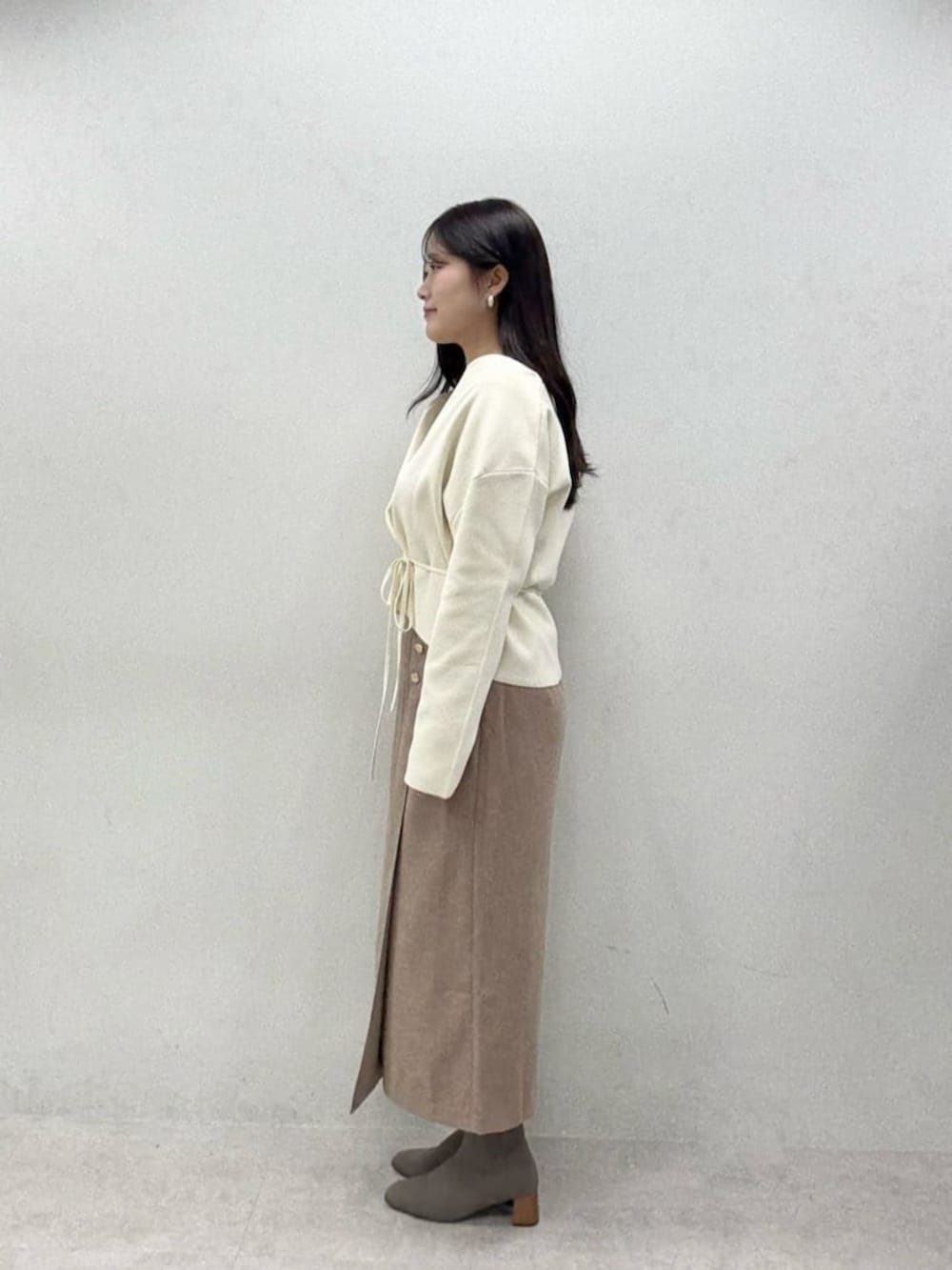 ブラウン系のスカート、グレー系のTシャツ/カットソー、ホワイト系のカーディガン/ボレロを着用したレディースの秋コーディネートの2枚目の写真