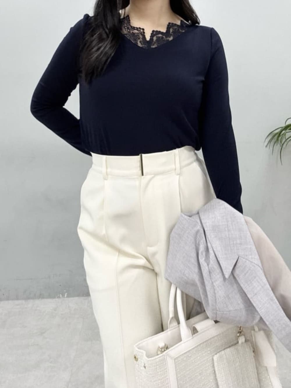 グレー系のテーラードジャケット、ホワイト系のハンドバッグ、ホワイト系のスラックスを着用したレディースの春コーディネートの5枚目の写真